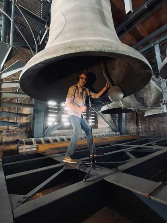 Komponist Chistian Biegai unter eine tonnenschweren Glocke eines Glockenspiels bei der Aufnahme